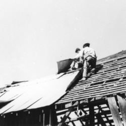 Unknown individuals working on a roof of barn